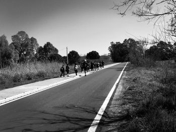 People walking on road against clear sky