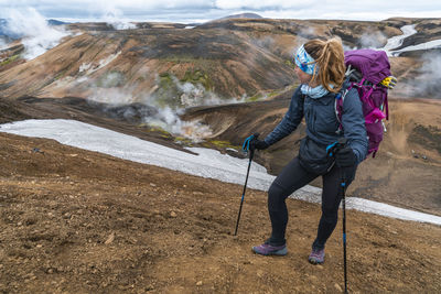 Female hiker watching steam vents while hiking laugavegur trail