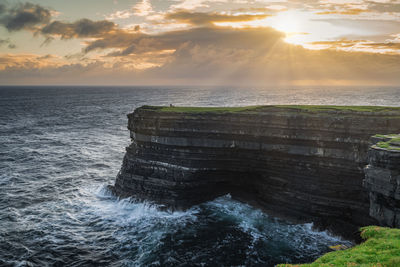 Fisherman standing and fishing from the edge of tall downpatrick head cliffs, ireland