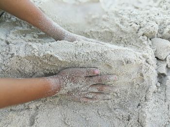 High angle view of hands on sand