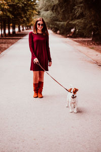 Young woman with dog walking on footpath