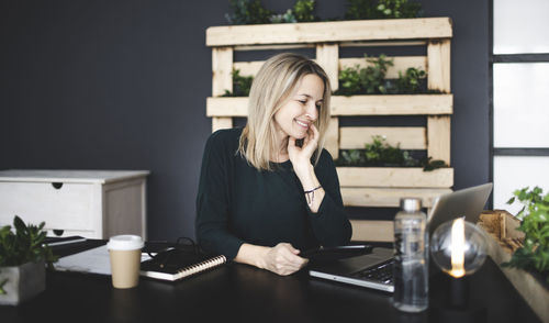 Smiling businesswoman looking at laptop in office