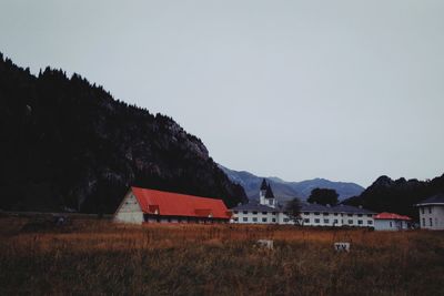 Houses by trees and mountains against clear sky