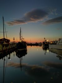 Boats moored at harbor against sky during sunset