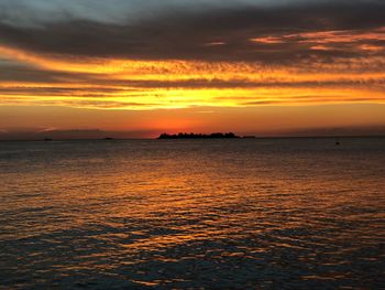 Scenic view of sea against dramatic sky during sunset