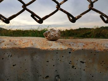 Close-up of rusty metal fence against sky