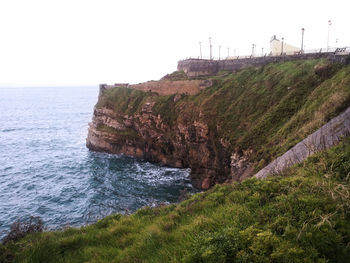 Scenic view of cliff by sea against clear sky