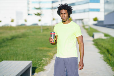 Man with insulated drink container standing in park