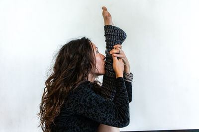 Side view of woman stretching against wall