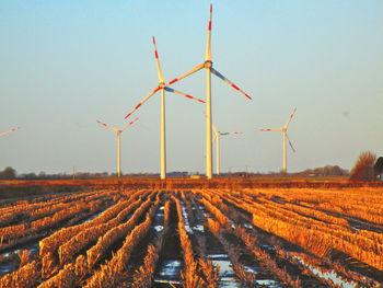 Wind turbines on field against clear sky