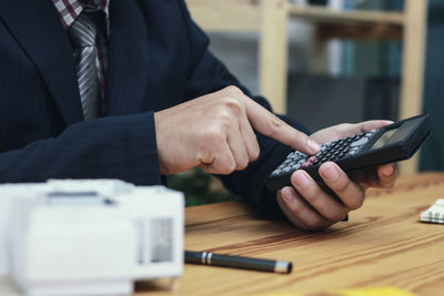 Midsection of man using mobile phone on table