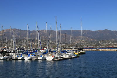 Sailboats moored on sea against clear blue sky