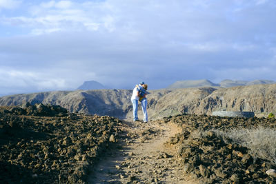 Rear view of man standing on mountain against sky