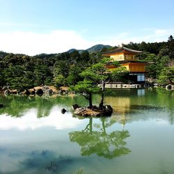 Scenic view of lake by trees and building against sky