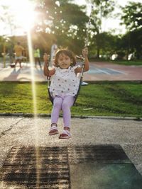 Full length portrait of girl swinging on playground