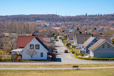 Houses on road by buildings against clear sky