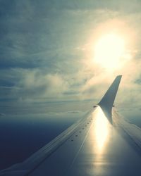 Cropped image of airplane wing over clouds