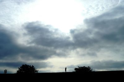 Silhouette of trees against cloudy sky