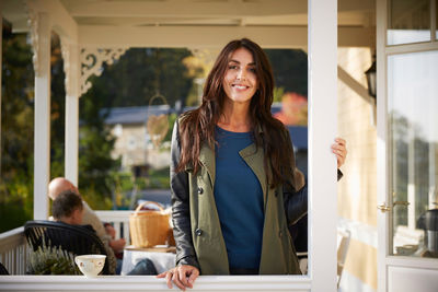 Portrait of confident smiling mature woman standing on porch