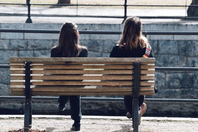 Rear view of woman sitting on bench in park