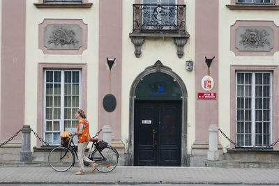 Side view of man cycling on street against building