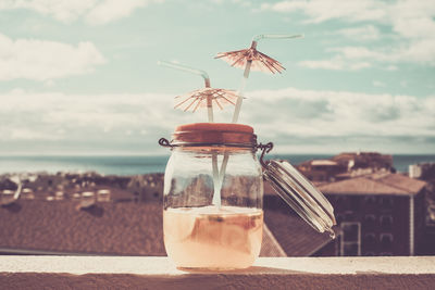 Close-up of drink in jar against sea and sky