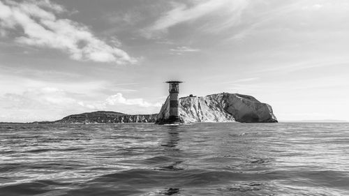 Lighthouse by sea against sky