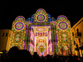 Crowd of illuminated ferris wheel against sky at night