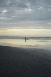 Silhouette person standing on beach against sky during sunset