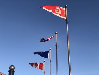 Low angle view of flag flags against clear blue sky