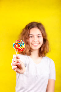 Portrait of a smiling young woman against yellow background