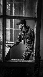 Man looking through window while standing in abandoned building