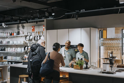 Sales clerks discussing with customers while using modern kitchen appliances at store