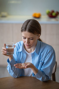 Sad alone woman suffering depression taking antidepressants neuroleptics drinking water feeling bad