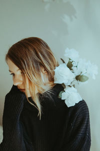 Close-up of woman with pink flowers against wall