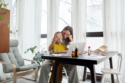 Mother with sick son looking at laptop