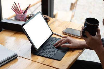 Close up hand of woman using blank screen digital tablet while working on his project.