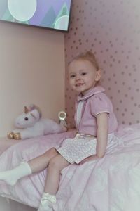 Cute girl sitting on bed at home