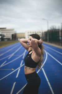 Young woman looking away while standing against sky