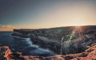 Scenic view of sea against sky during sunset with waterfalls