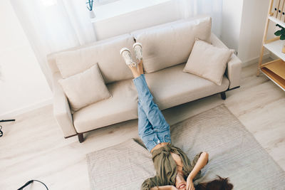 Low section of woman sitting on sofa at home