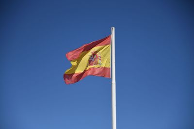 Low angle view of flag against blue sky