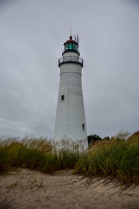 Low angle view of lighthouse amidst buildings against sky