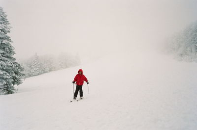 Rear view of person walking on snow covered mountain