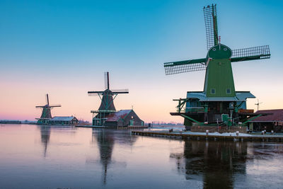 Traditional windmill by water against clear sky