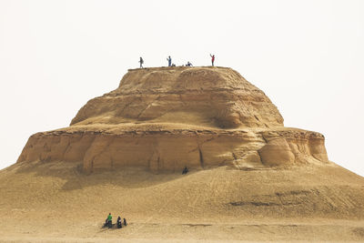 Low angle view of woman walking on desert against clear sky