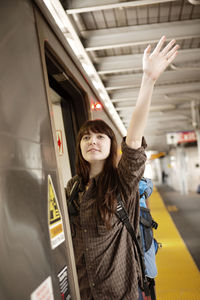 Woman waving hand while leaning out of train