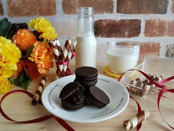 High angle view of sweet food with milk on table against brick wall