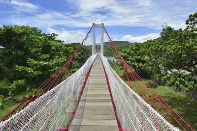 Footbridge amidst trees against sky