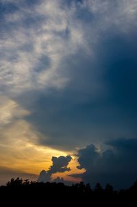 Low angle view of silhouette trees against dramatic sky